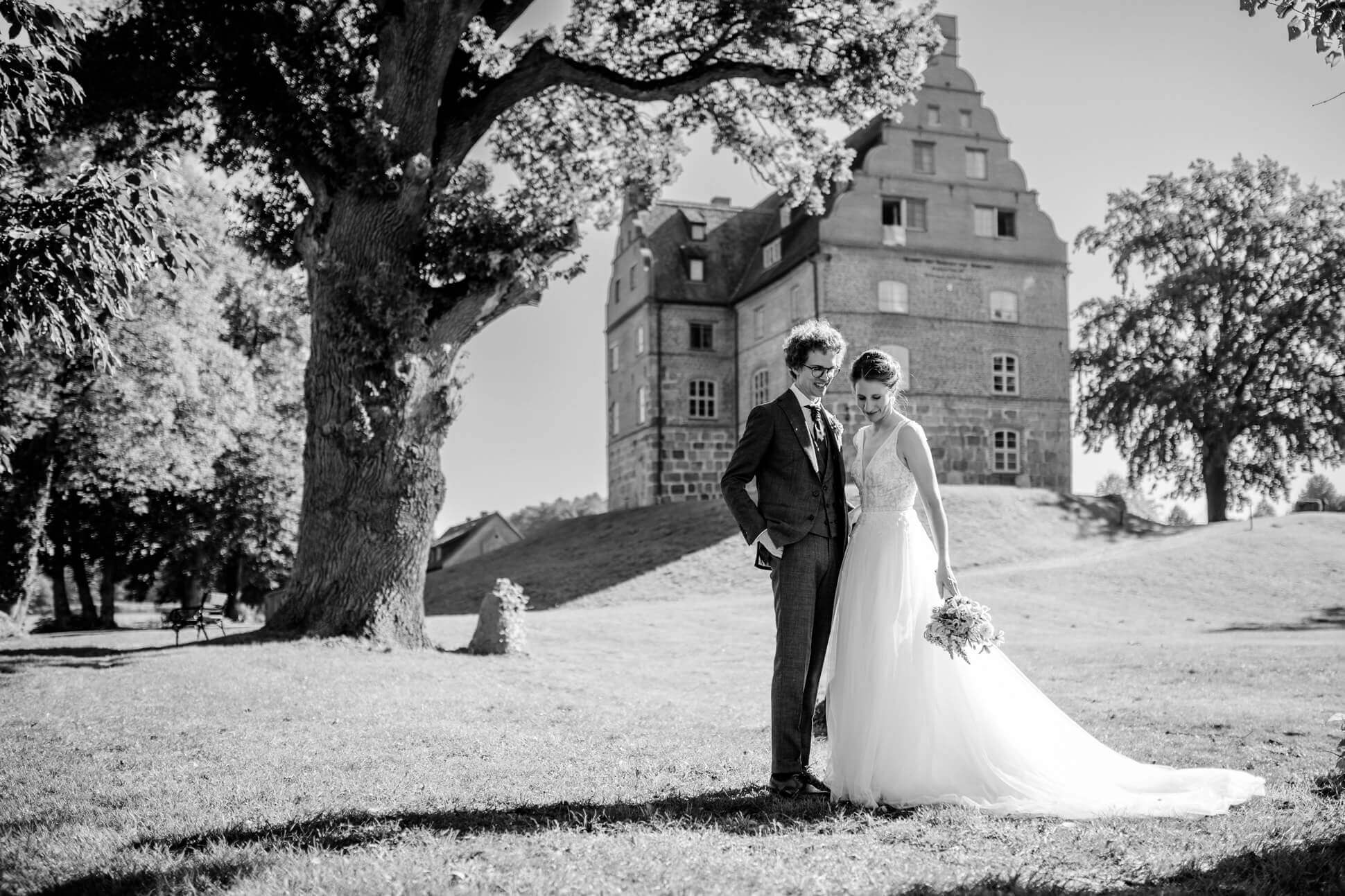 Schwarz weiß Aufnahme vom Brautpaat vor Schloss und Gut Ulrichshusen, aufgenommen von der Hochzeitsfotografin Mecklenburg