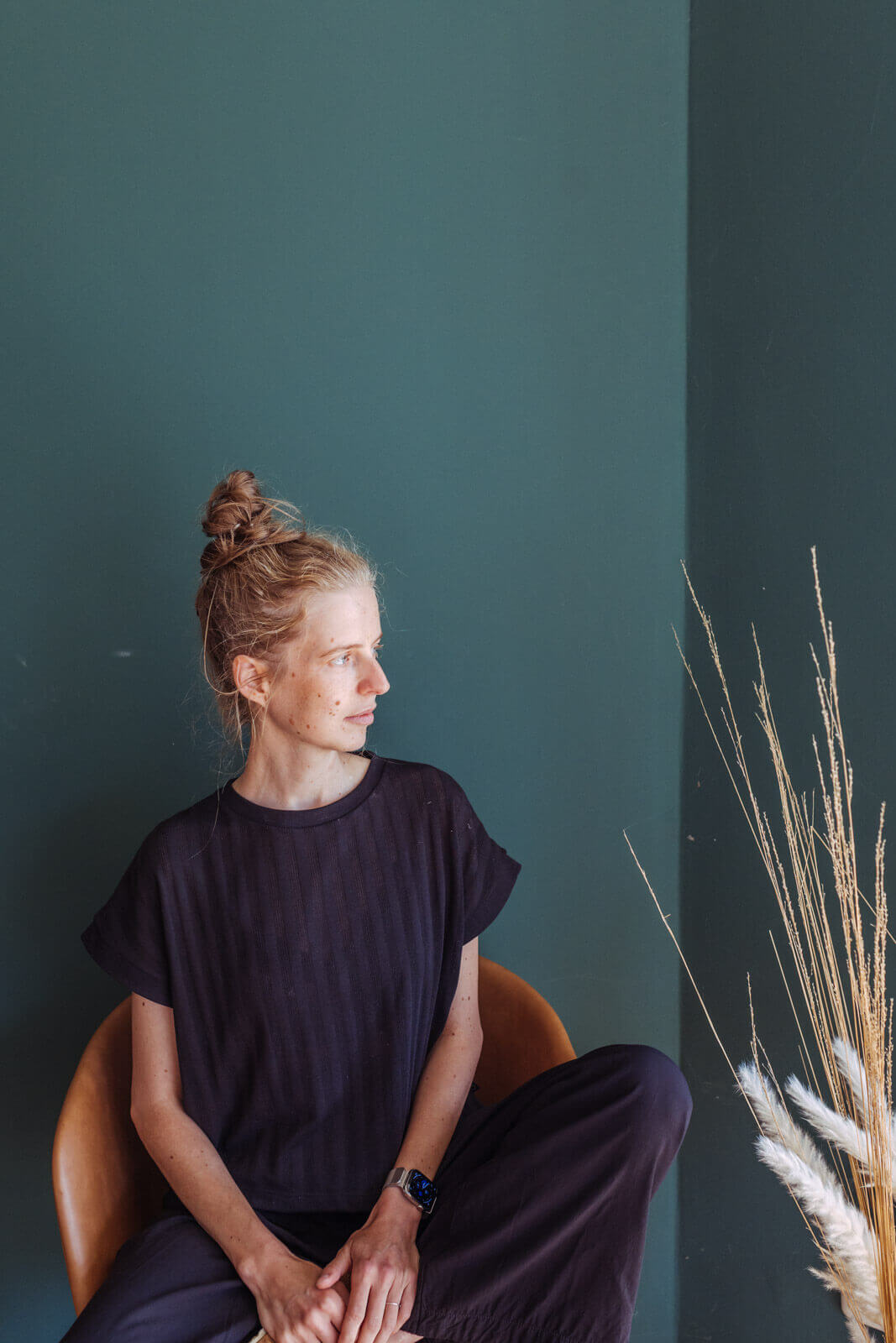 Die Fotografin aus Ueckermünde sitzt in einem Zimmer auf einem Stuhl vor einer dunkelgrünen Wand und schaut nachdenklich aus dem Fenster