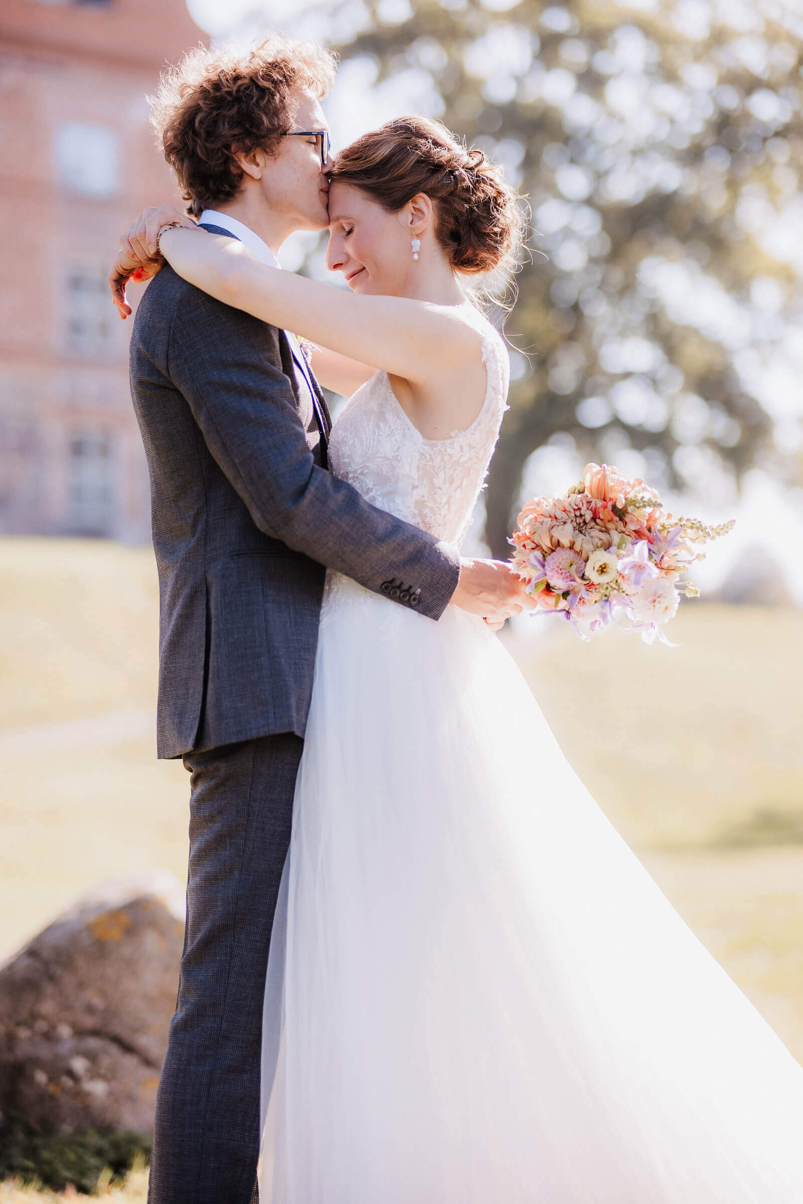 Brautpaar beim Shooting vor dem Schloss Ulrichshusen. Er küsst sie zärtlich auf die Stirn. Festgehalten von der Hochzeitsfotografin. 