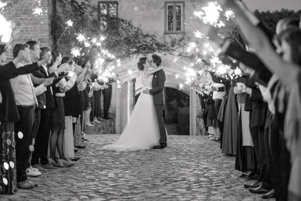 Brautpaar inmitten des Sparkling Exit Spalier mit Wunderkerzen, küsst sich in Mecklenburg