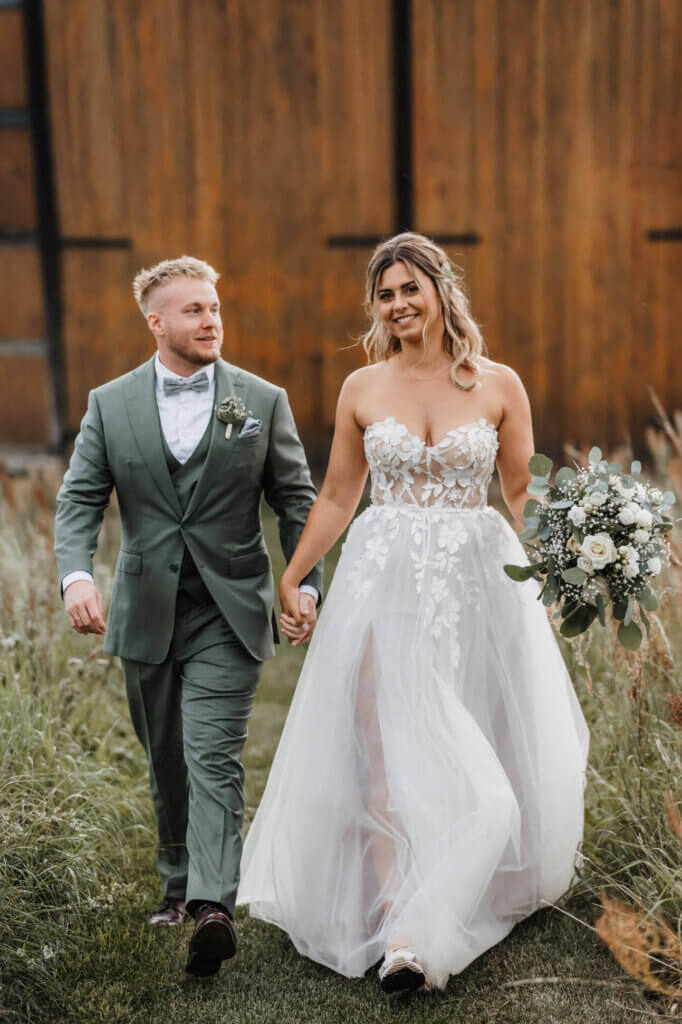 Das Brautpaar läuft Hand in Hand auf die Hochzeitsfotografin Brandenburg zu, Boho-Vibes