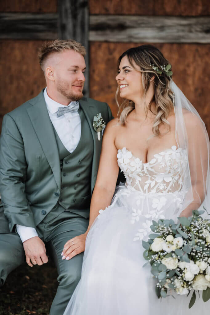 Hochzeitspaar sitzt beim Paarshooting auf einer Bank und schaut sich an, fotografiert von der Hochzeitsfotografin Brandenburg