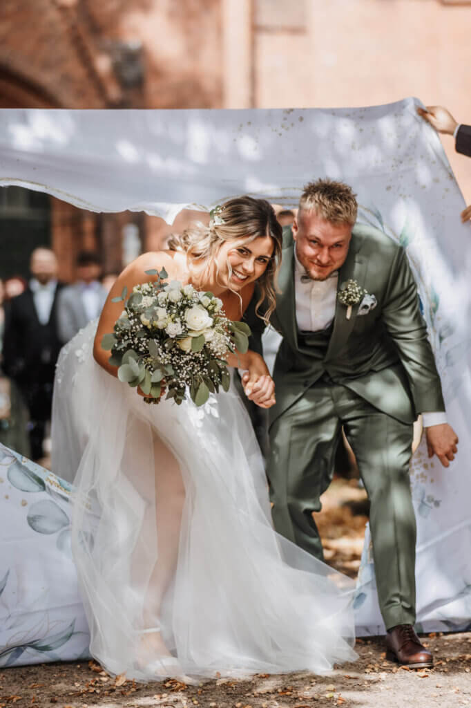 Brautpaar steigt nach der Trauung durch das ausgeschnittene Herz, Hochzeitsreportage Brandenburg