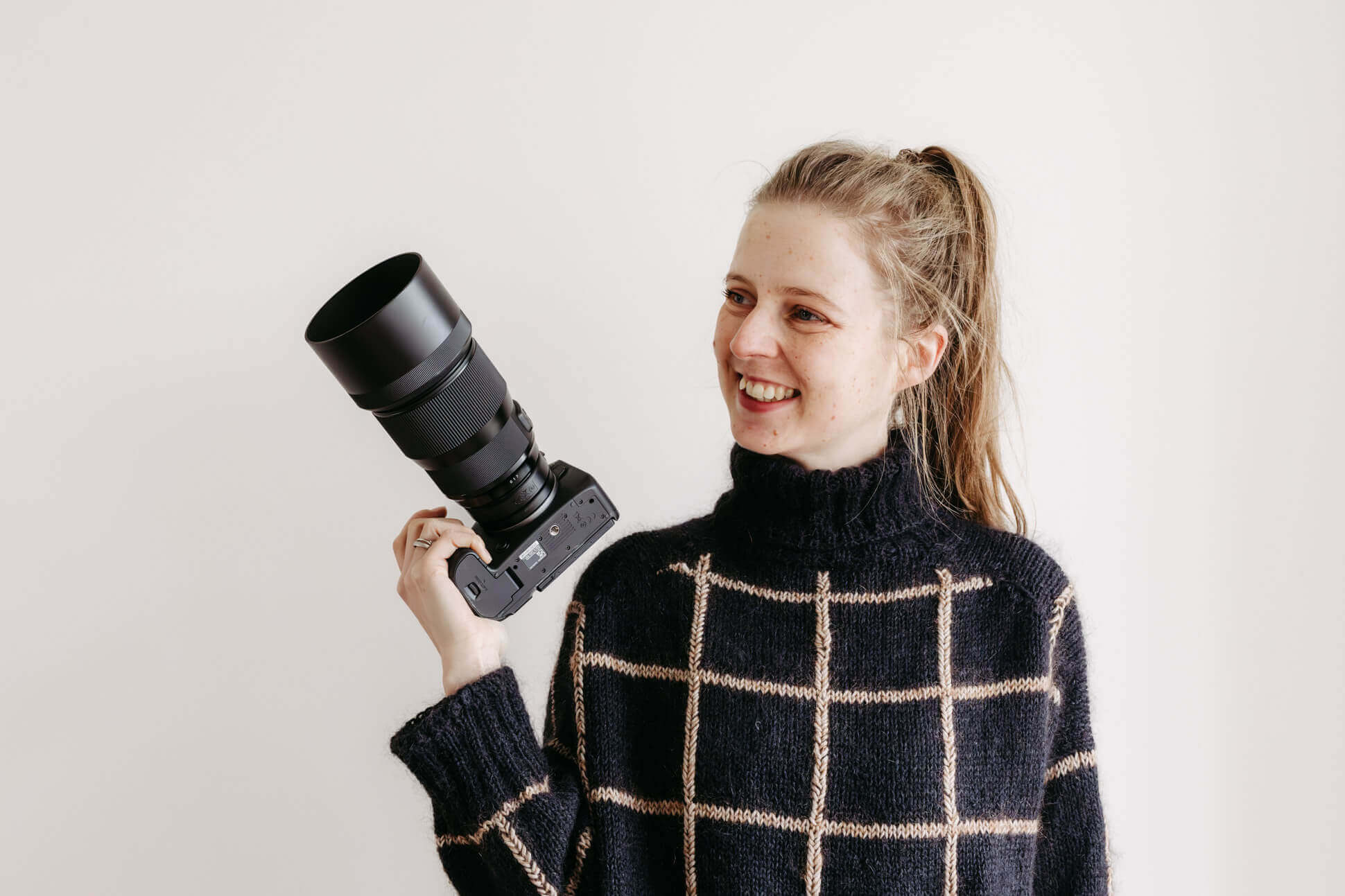 Studioaufnahme der Fotografin mit Kamera in der Hand, lachend