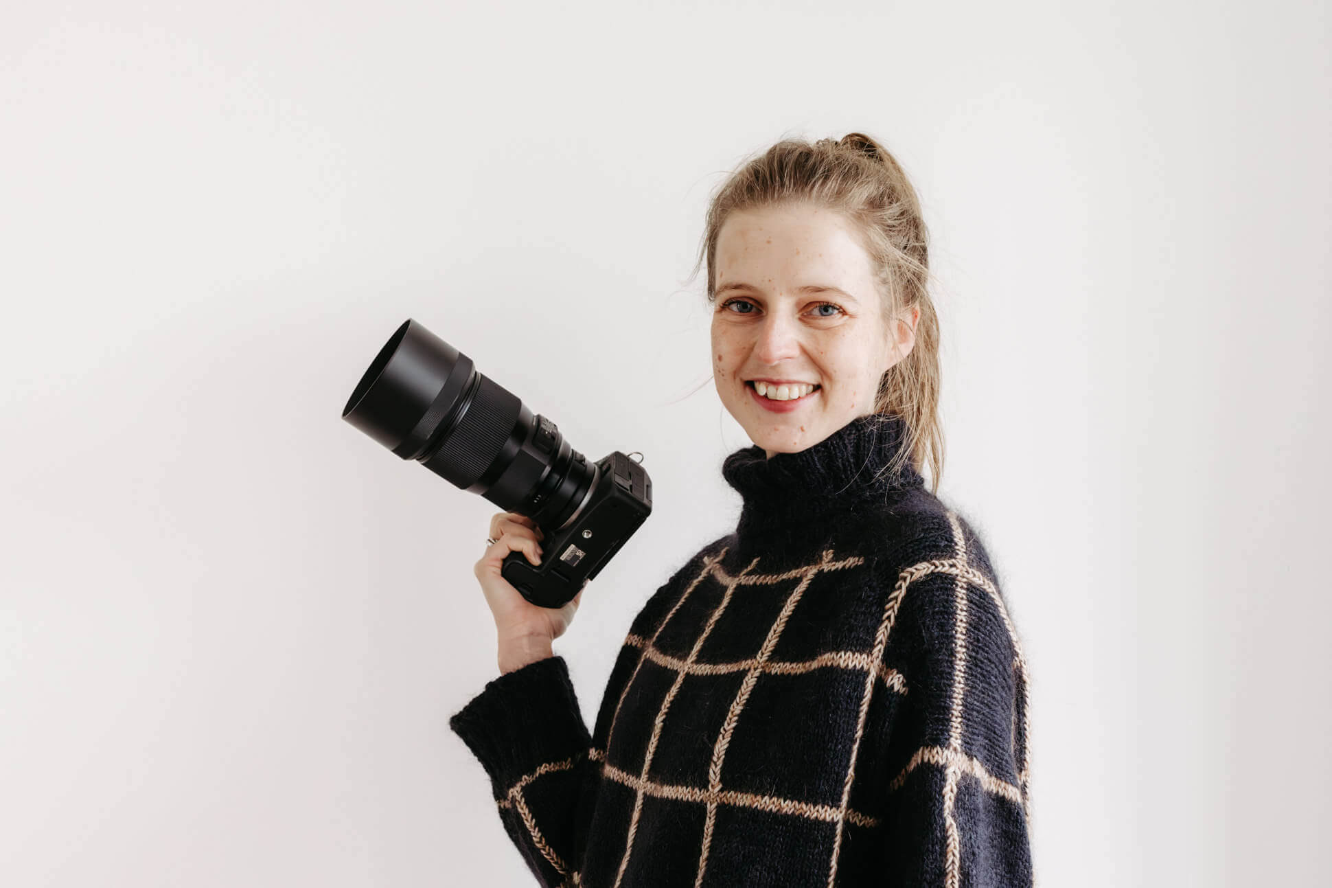 Studioaufnahme der Fotografin mit Kamera in der Hand, lachend