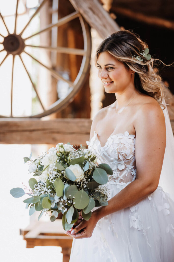 wunderschöne helle Boho-Aufnahme der Braut mit ihrem Brautstrauß in der Feldscheune Schöbendorf, fotografiert von der Hochzeitsfotografin Brandenburg