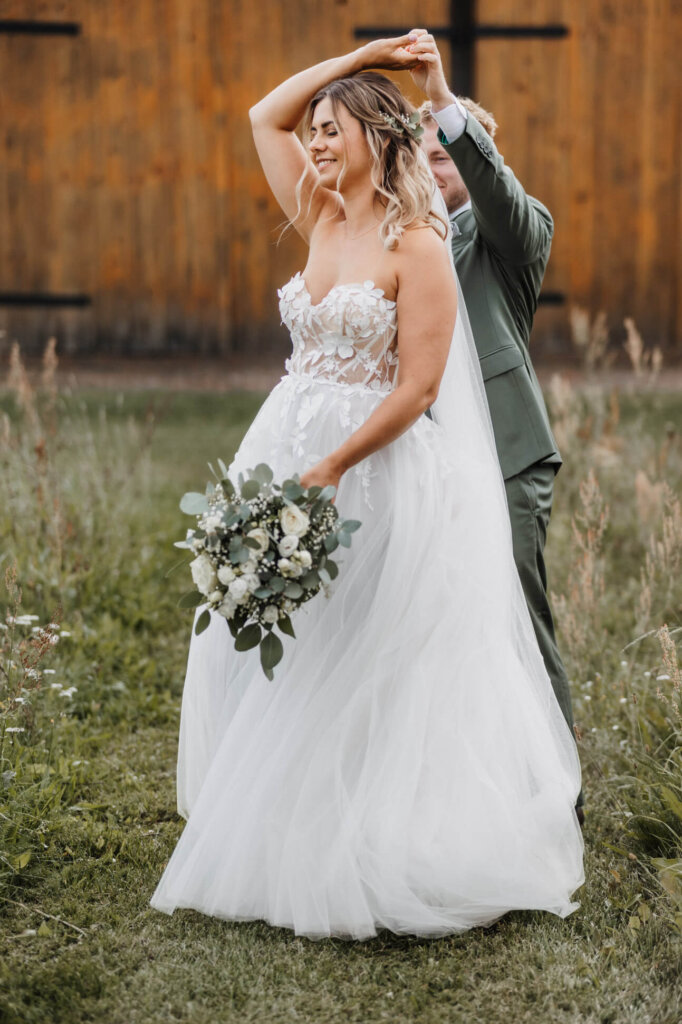 Das Brautpaar tanzt auf der Wiese vor der Feldscheune Schöbendorf, fotografiert von der Hochzeitsfotografin Brandenburg