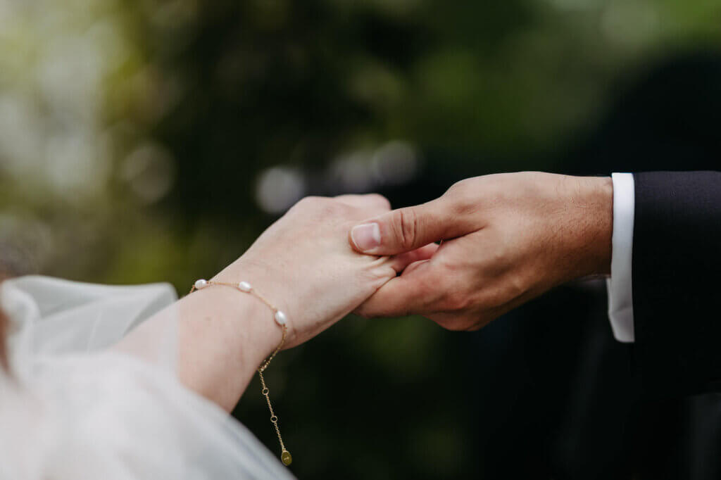 Hände der Brautleute bei der Trauung in Nahaufnahme, man sieht die Ringe und das Armband der Braut, fotografiert von der Hochzeitsfotografin Brandenburg