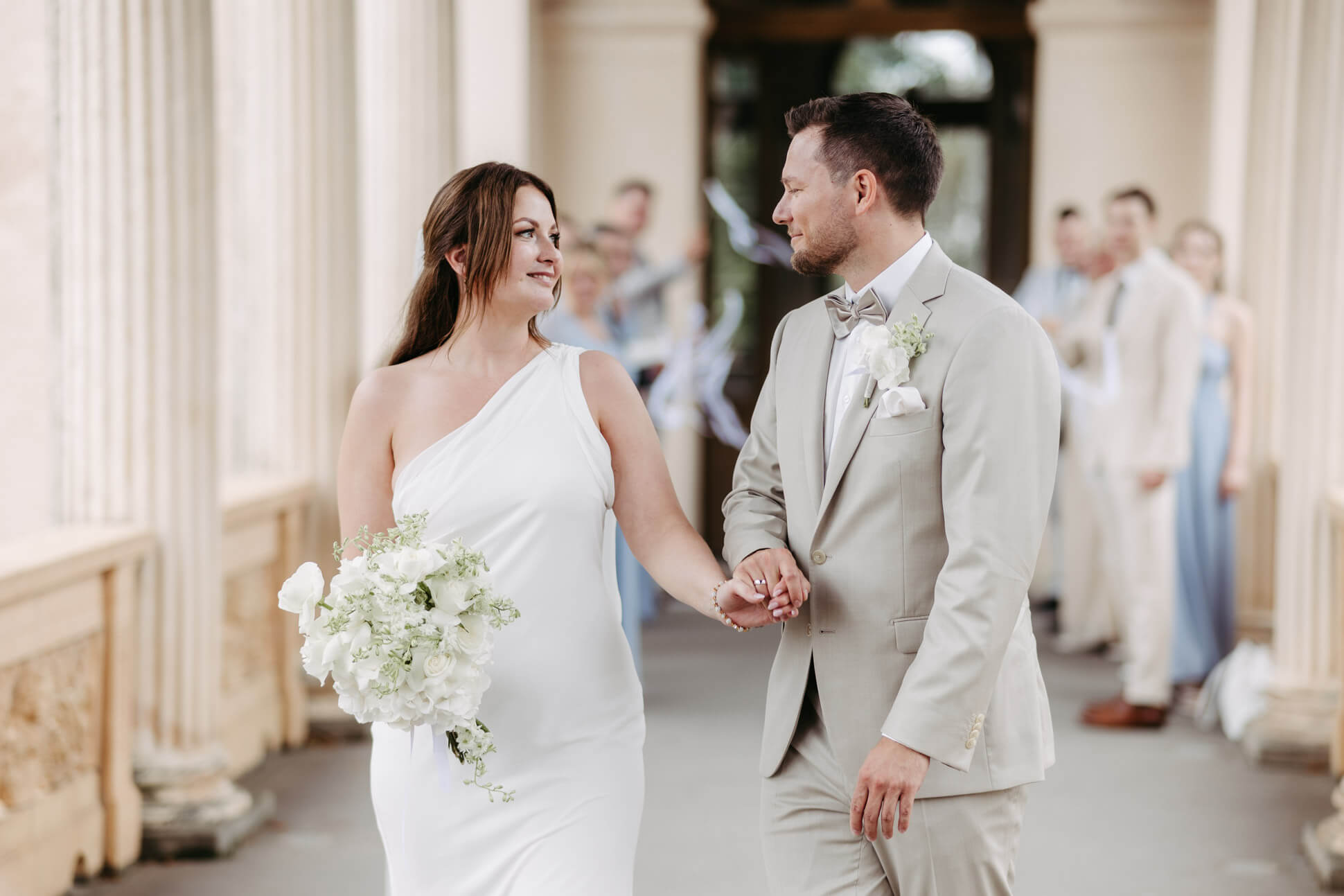 Brautpaar läuft nach dem Spalier in Potsdam Belvedere Hand in Hand und lacht sich verliebt an, fotografiert von der Ueckermünder Hochzeitsfotografin