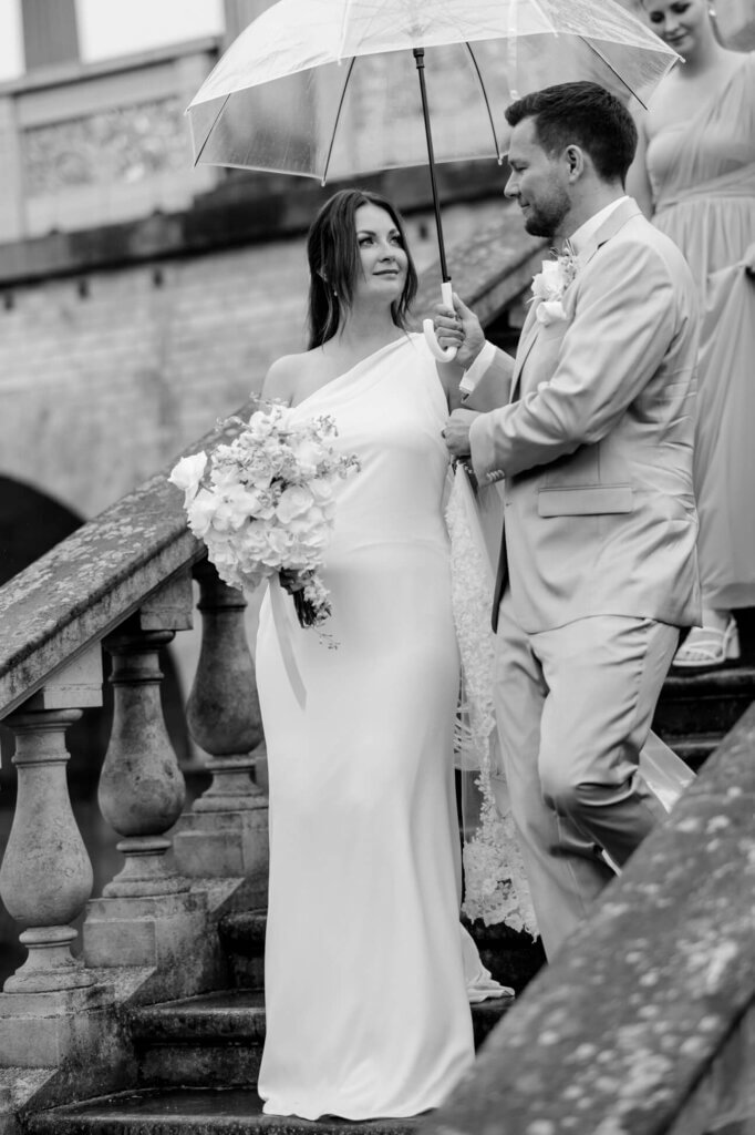 Das Paar schreitet die Treppe hinunter, einen Regenschirm in der Hand