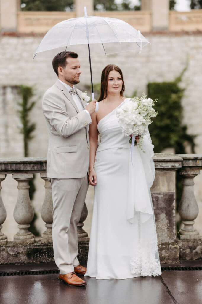 Das Brautpaar steht unter einem Regenschirm