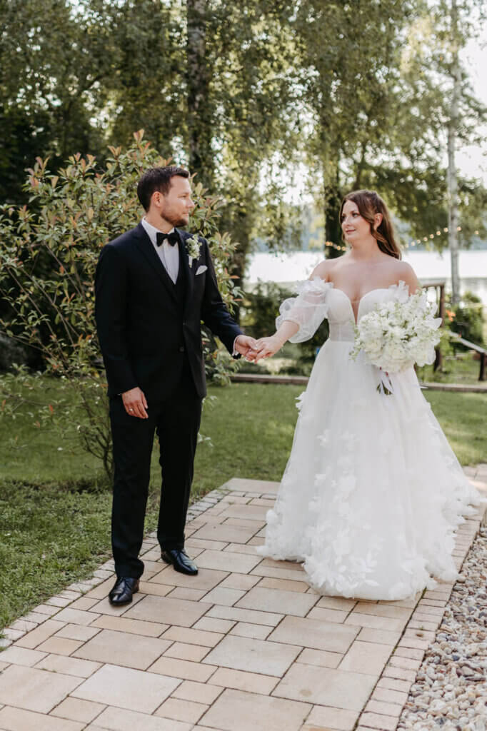 Das Hochzeiitspaar Hand in Hand und mit verliebtem Blick