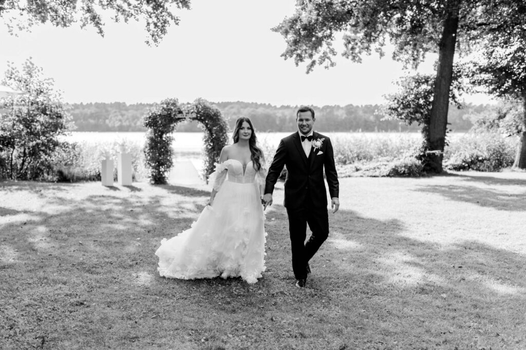 Brautpaar läuft Händchen haltend über die Wiese in Brandenburg