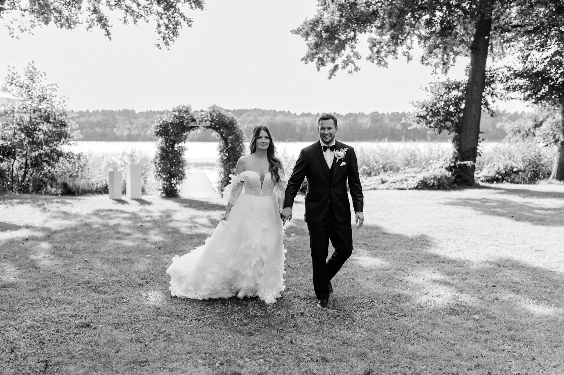 Brautpaar läuft Händchen haltend über die Wiese in Brandenburg