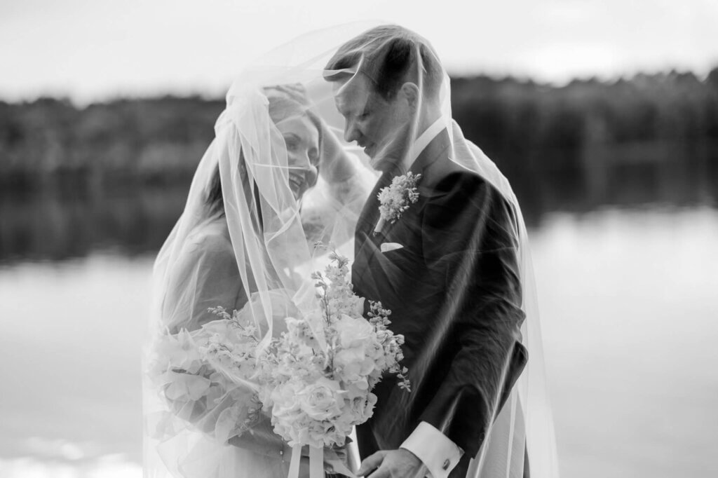 Brautpaar lachend unter dem Schleier am See Villa Zesch
