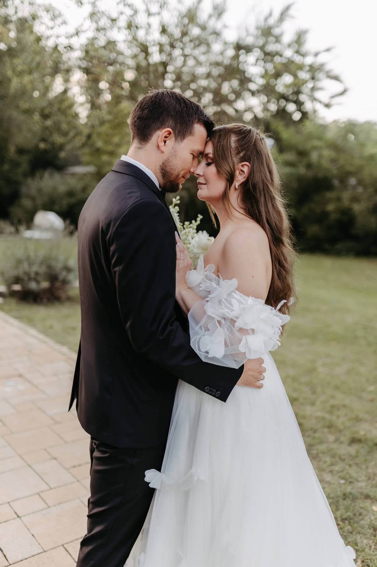 Innige Umarmung des Brautpaares in mediterranem Garten der Villa Zesch am See