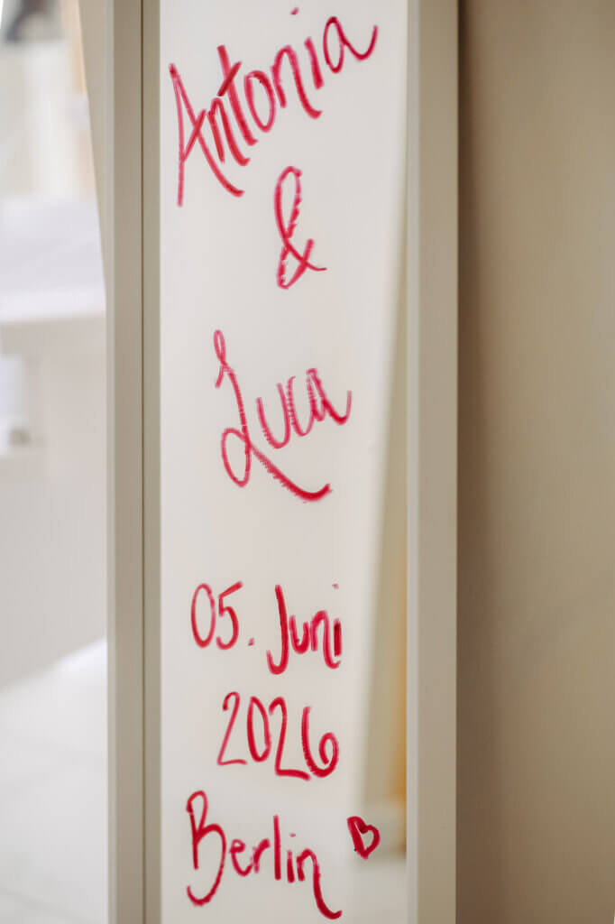 Mit Lippenstift für das Hochzeitspaar beschriebener Spiegel